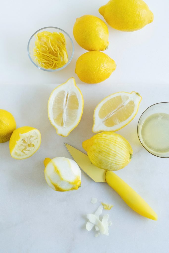 lemons and cup full of lemon peel/lemon zest with a yelklow knife